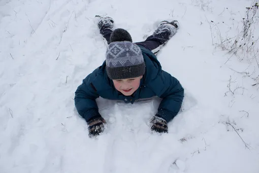Мальчик лежит на снегу