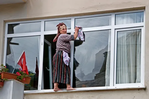 Жительница стамбульского района Истинье моёт окна в своём доме