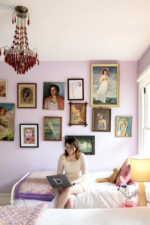Розовая стена с галереей картин и девушкой, сидящей на кровати