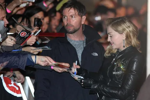 Мадонна раздает автографы поклонникам под присмотром телохранителя