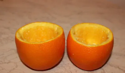 Для начала подготовим апельсиновые чашечки. У апельсина необходимо отрезать верхушку‚ вынуть мякоть‚ оставив целыми чашечки и немного срезать низ для устойчивости
