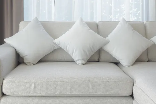 Подушки и диван цвета белой ночи с прозрачной шторой на заднем плане