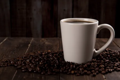 Чашка с кофе в кофейных зернах