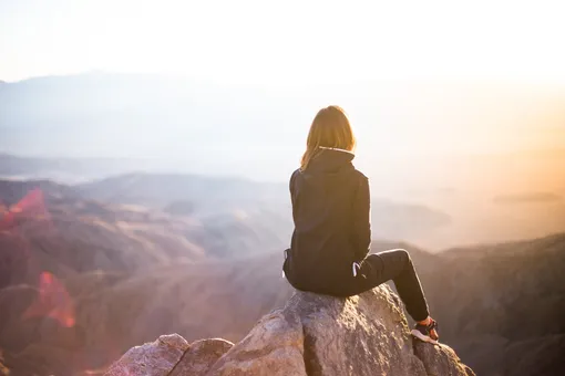 Девушка сидит на фоне скал