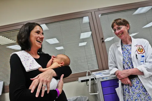 Женщина с новорожденным и врач смеются
