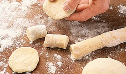 Разделите тесто на части, скатайте колбаски и нарежьте на кусочки толщиной 1 см. Раскатайте их в небольшие тонкие лепешки или разомните пальцами.