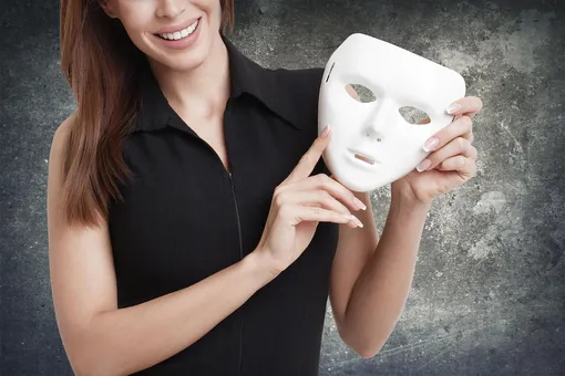 Улыбающаяся девушка держит в руках белую маску, синоним двойной жизни, афоризмы про ложь