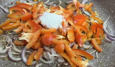 Следом полукольцами нарезаем лук, а болгарский перец длиной соломкой и обжариваем всё на растительном масле в течение 7-8 минут до мягкости и золотистого цвета.