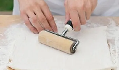 Приготовьте начинку: картофель очистите, отварите, разомните толкушкой и заправьте ароматным маслом и горчицей, добавьте измельченный укроп. 
Грибы очистите, произвольно нарежьте и обжарьте в сковороде на растительном масле до готовности. Раскатайте тесто на присыпанной мукой поверхности в тонкий прямоугольный пласт узкой частью к себе.