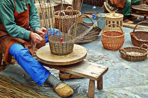 мужчина плетет корзину из прутьев
