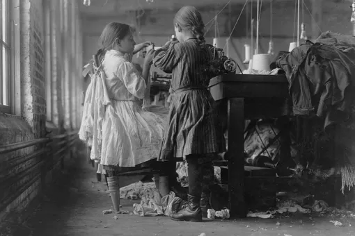 Две маленькие девочки работают распутывателем и петлителем на чулочно-носочной фабрике.