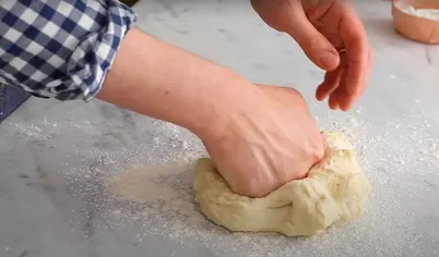 Переложите тесто для пиццы на присыпанную мукой поверхность и продолжайте вымешивать, пока не сформируется гладкий упругий шар.
