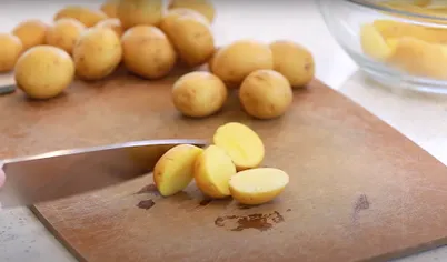 Разогрейте духовку до 200 градусов. Разрежьте картофель пополам или на четвертинки. Положите в миску, сбрызните оливковым маслом, приправьте солью, перцем и чесноком. Перемешайте, чтобы картошка полностью покрылась заправкой.
