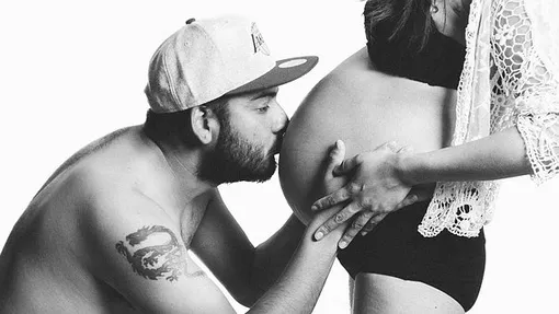 бородатый мужчина целует живот беременной женщины
