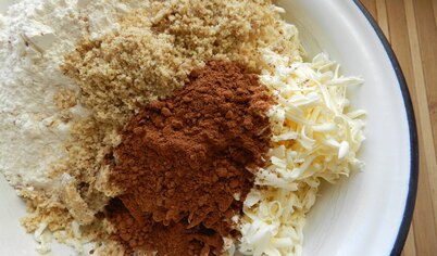 Грецкие орехи измельчить в блендере.
Масло натереть на терке, соединить с мукой, измельченными орехами, ванильным сахаром и какао.
Руками растереть в однородную крошку.