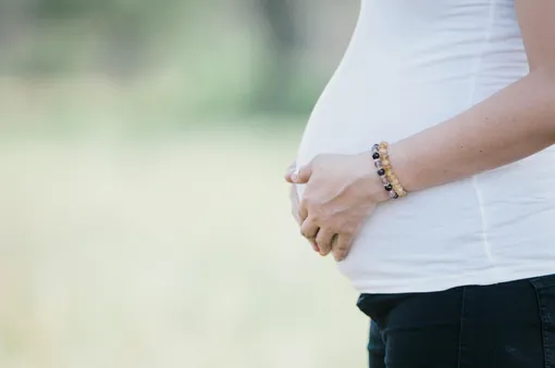 руки поддерживают беременный живот на 36 неделе беременности