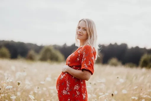 беременная девушка стоит в поле