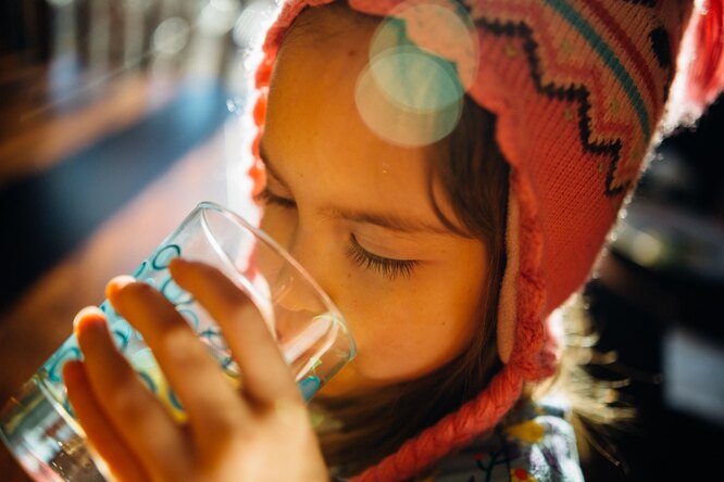Девочка пьет из чашки, пить полезно при высокой температуре