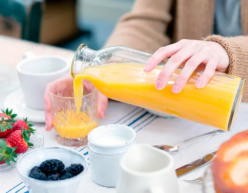 женщина наливает апельсиновый сок