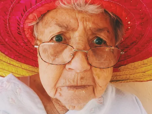 Пожилая женщина в красной шляпе и очках