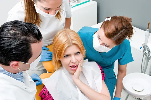 три стоматолога возле пациента