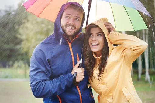 Парень и девушка улыбаются под зонтиком под дождем, позитивные цитаты про позитивное мышление