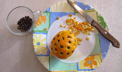 В апельсине прорезать отверстия и вставить кофейные зёрна.