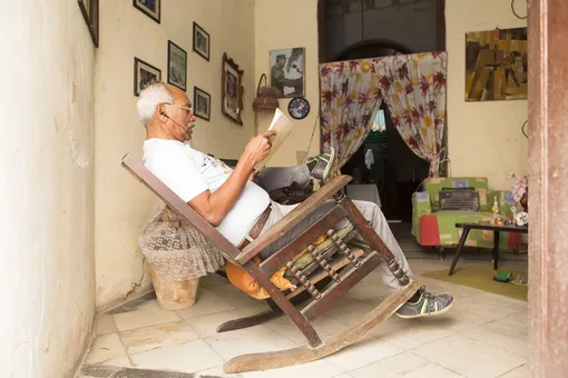 мужчина в кресле-качалке читает газету