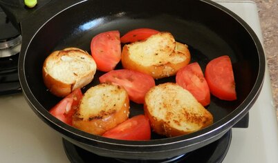 Добавить в сковороду дольки помидоров, быстро обжарить их с двух сторон.
