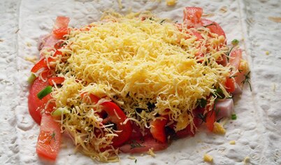 Порезать ветчину и помидор кубиками, перец полосками.Мелко порезать зелень. Выложить на лаваш, добавить взбитое яйцо,посолить. Посыпать тертым сыром.